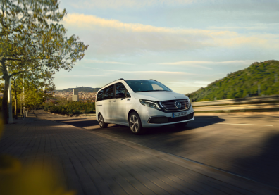a white Mercedes-Benz Vito driving on a road surrounded by trees and greenery